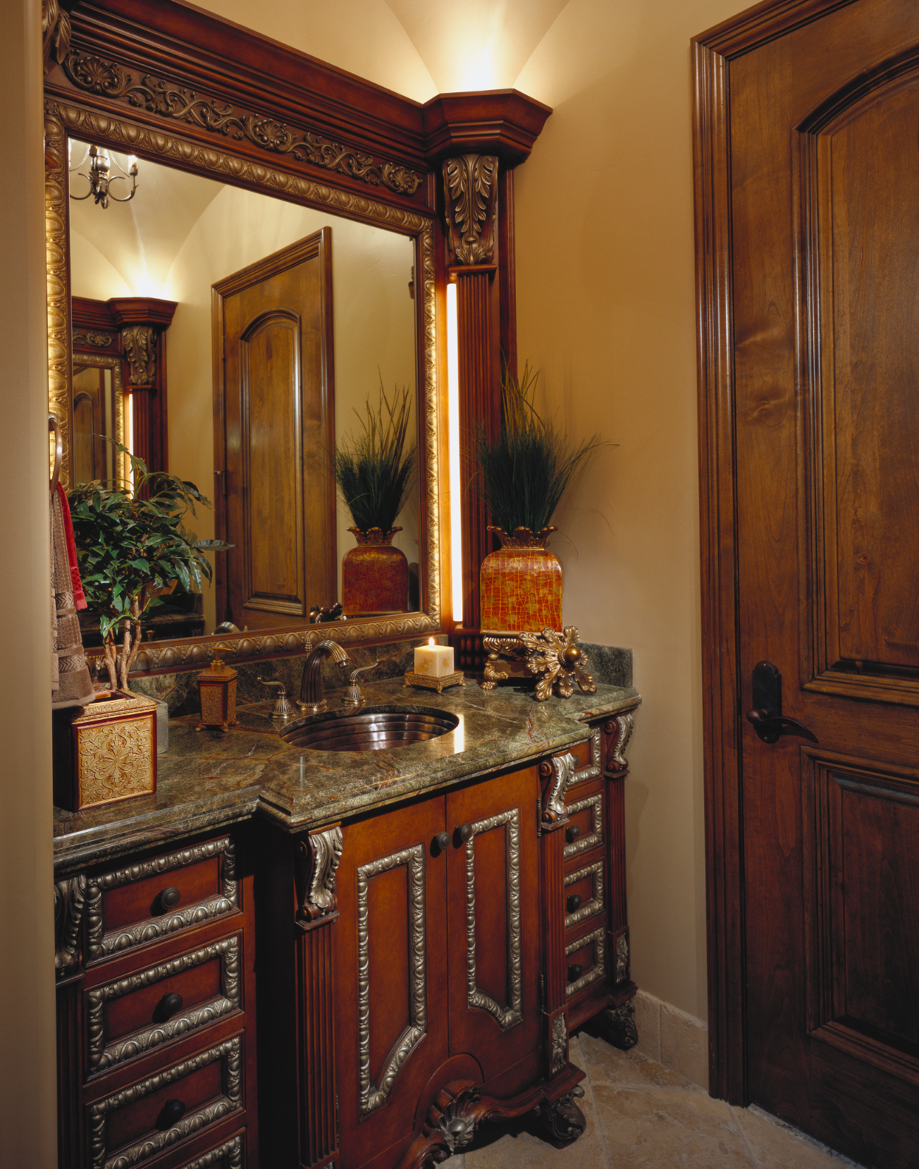Bathroom with dark wood vanity, ornate mirror, granite countertop, and matching door.