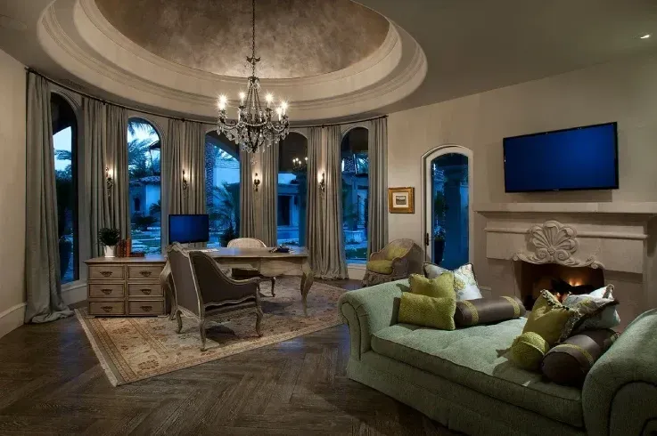 Elegant living room featuring a sculptural recessed ceiling, chandelier, arched windows, and classic furniture.