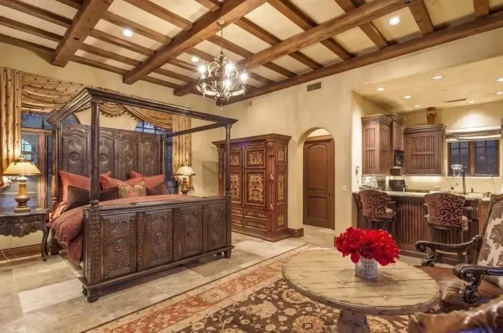 A bedroom with a canopy bed , a table , chairs , and a chandelier.