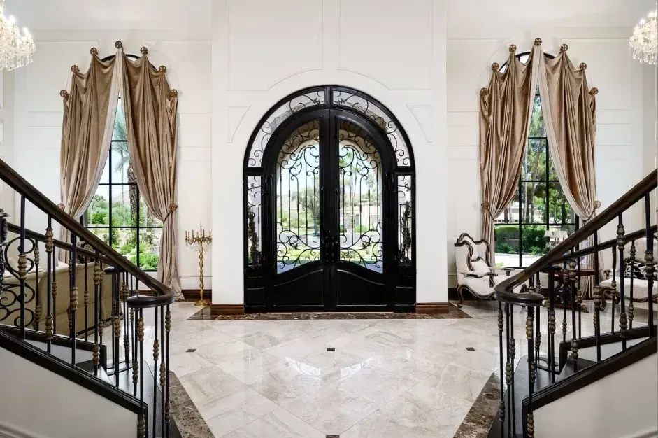 Grand entrance with double staircase, chandelier, and arched windows