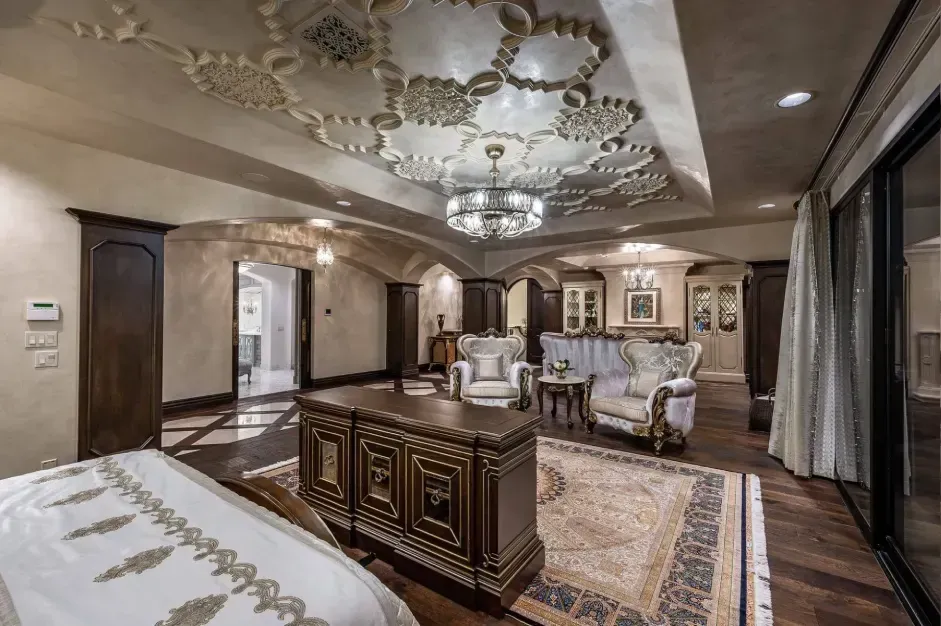 Spacious master suite with bed, seating area, and chandelier