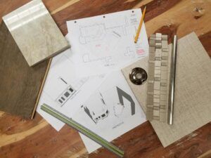 A wooden table topped with papers , a ruler , and a pencil.
