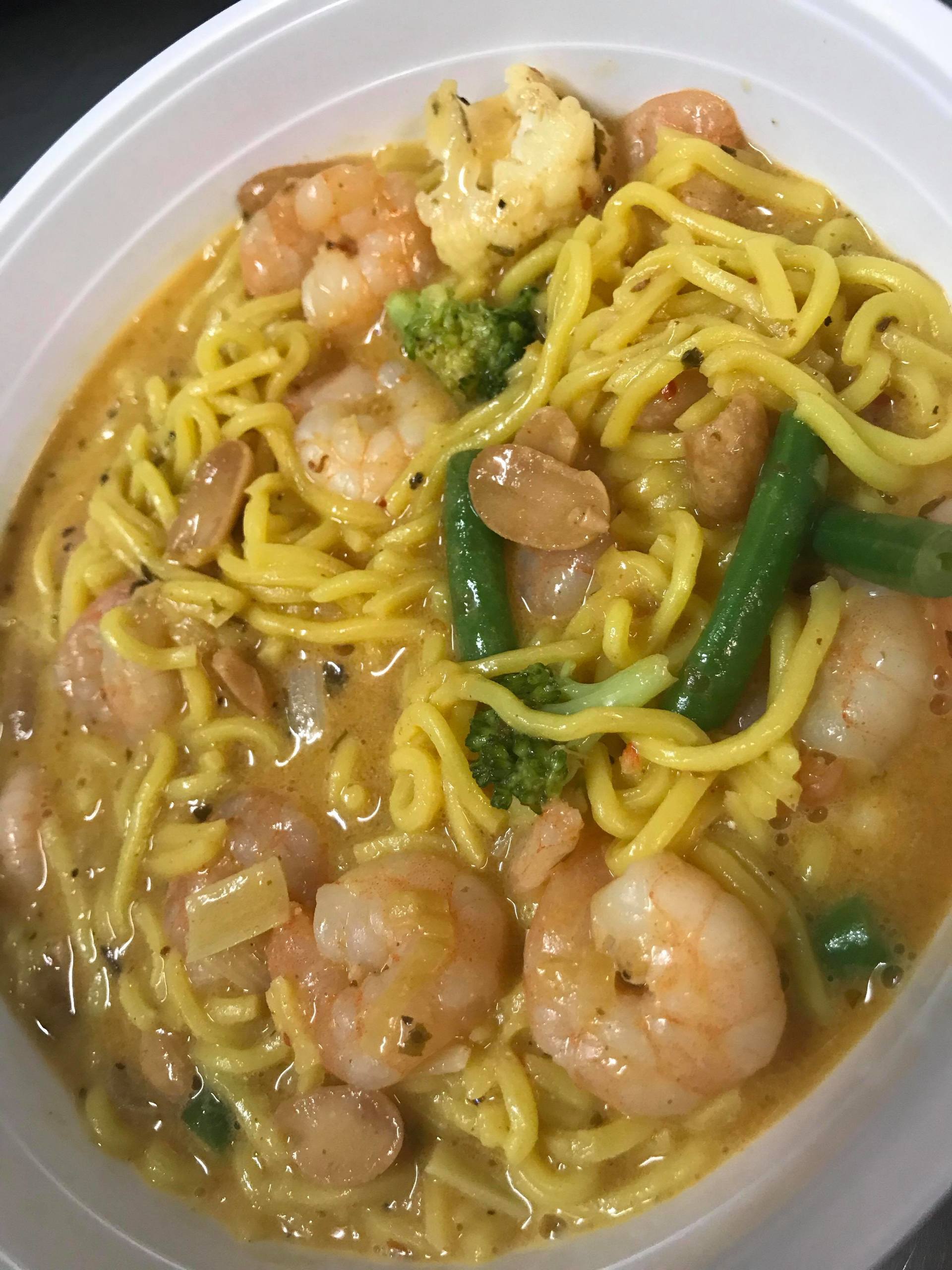 Bowl of noodle soup with shrimp, green beans, broccoli, and vegetables in a light broth