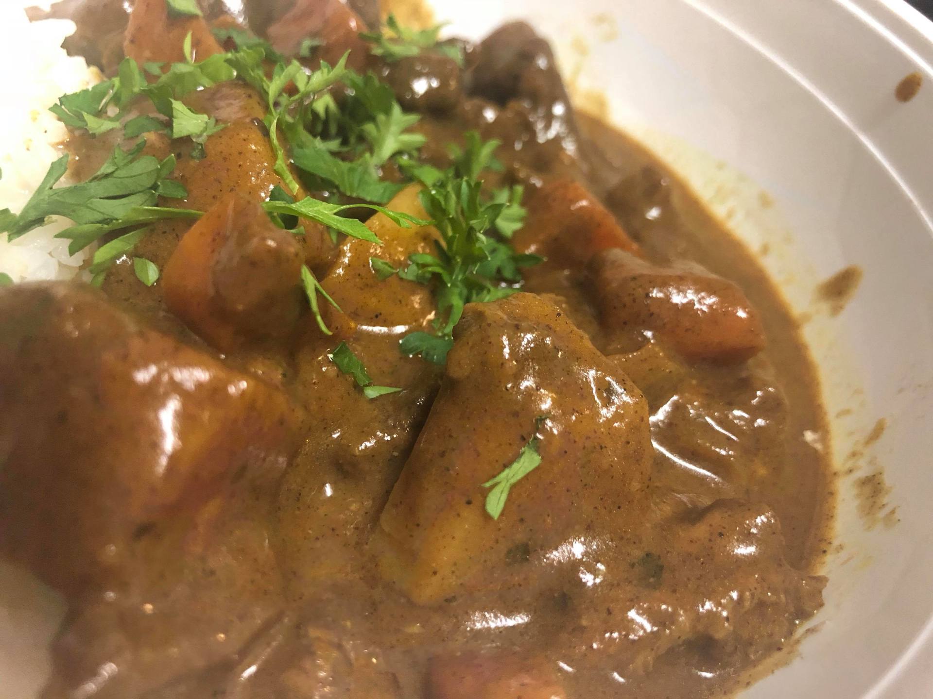 Brown stew with fresh cilantro garnish in a white bowl