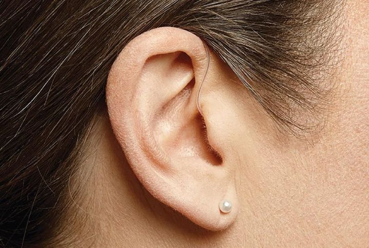 Close-up of an ear with a small pearl stud earring against brown hair.