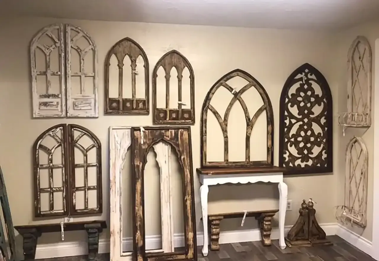 Assorted decorative arched window frames and wall panels are displayed in a room