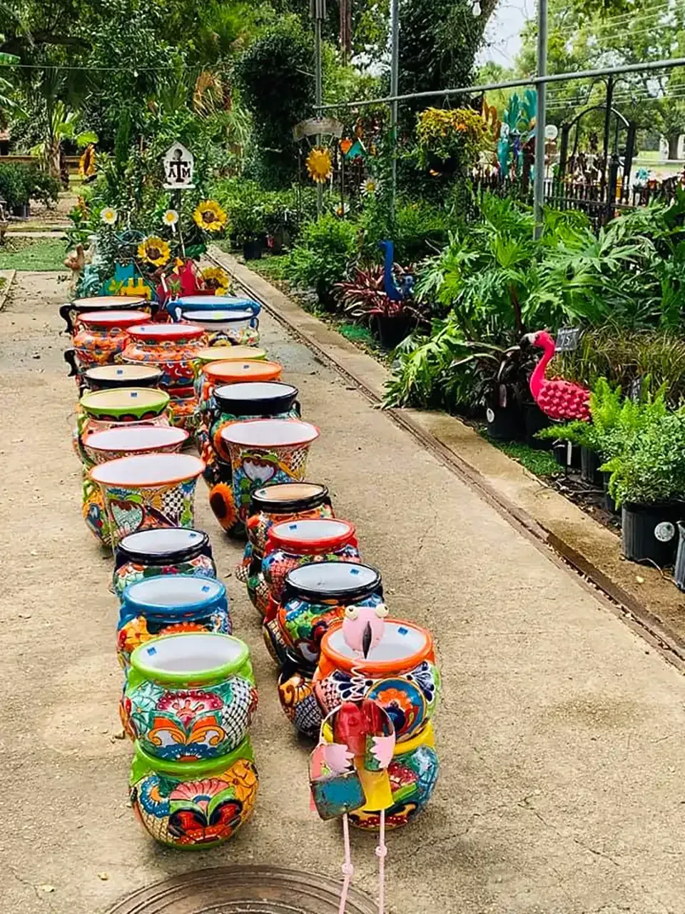 Colorful painted stools lined up along a garden path beside lush plants and flowers