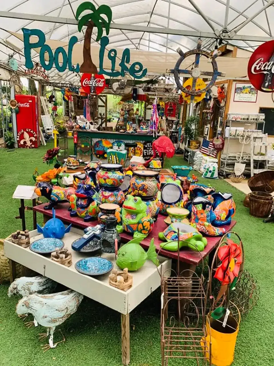 Colorful beach toys and floaties are displayed in a shop with a tropical “Pool Life” sign.
