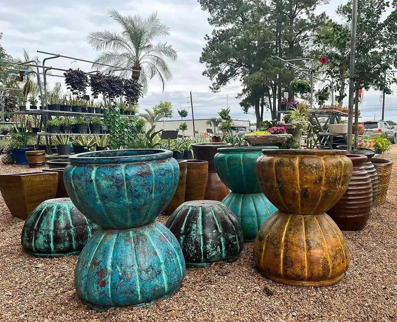 Colorful oversized ceramic planters in a garden display with trees and an ocean view in the background