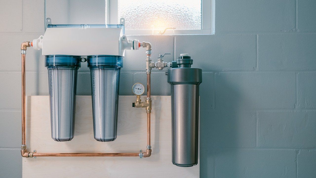 Two whole-house water filter housings and a carbon tank installed on the main water line in an Ohio Valley utility room