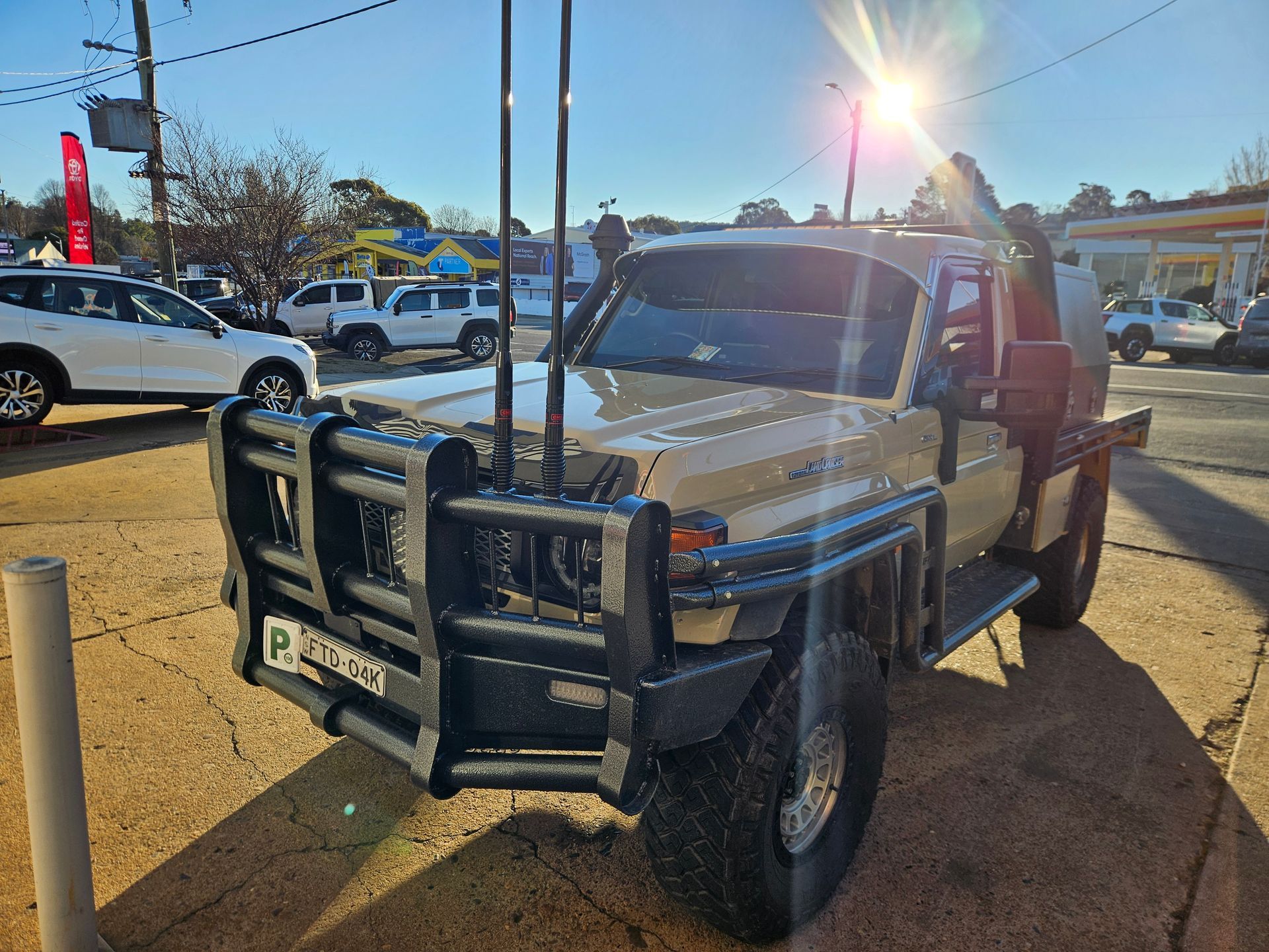 White pickup truck with heavy front grille guard parked in a sunny lot, front view