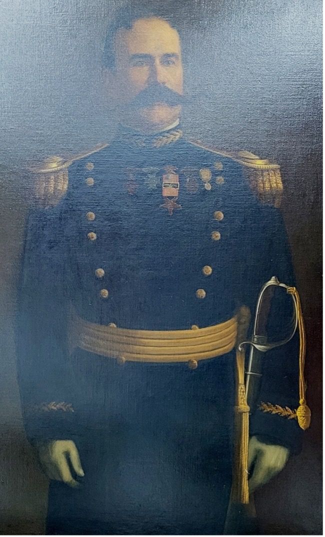 Man in a dark military uniform with gold accents and epaulets, holding a sword.