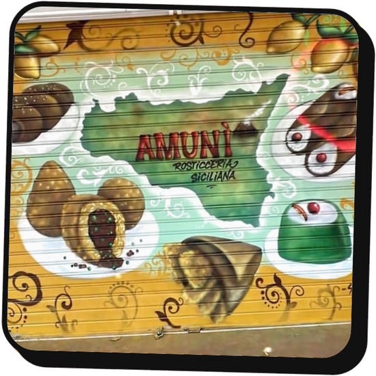 Murale colorato sulla saracinesca della panetteria Amuni, con pasticcini siciliani e mappa illustrata della Sicilia.