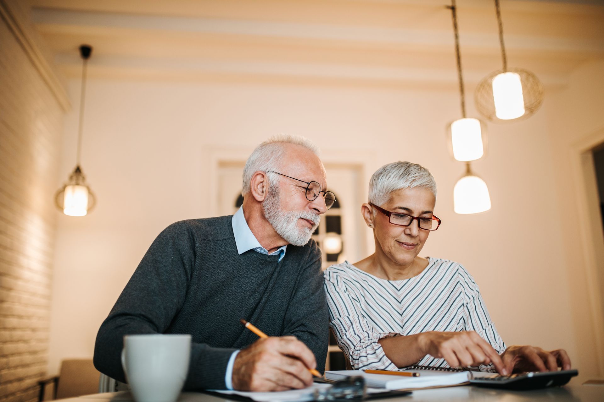 An elderly couple is sitting at a table using a calculator. fiancial planning