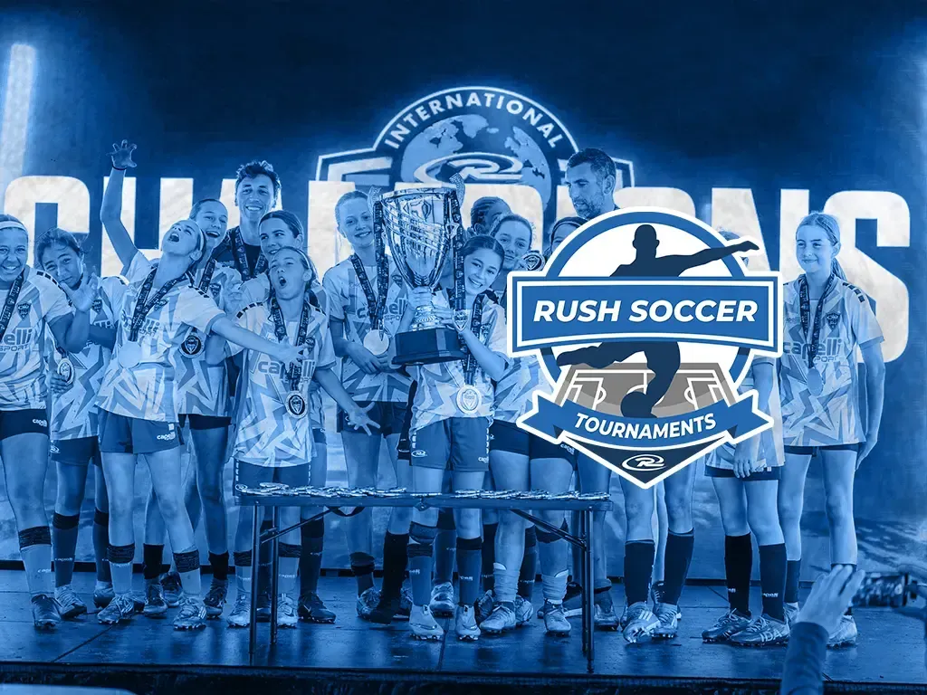Youth soccer teams celebrate on a podium with trophies at a Rush Soccer tournament.