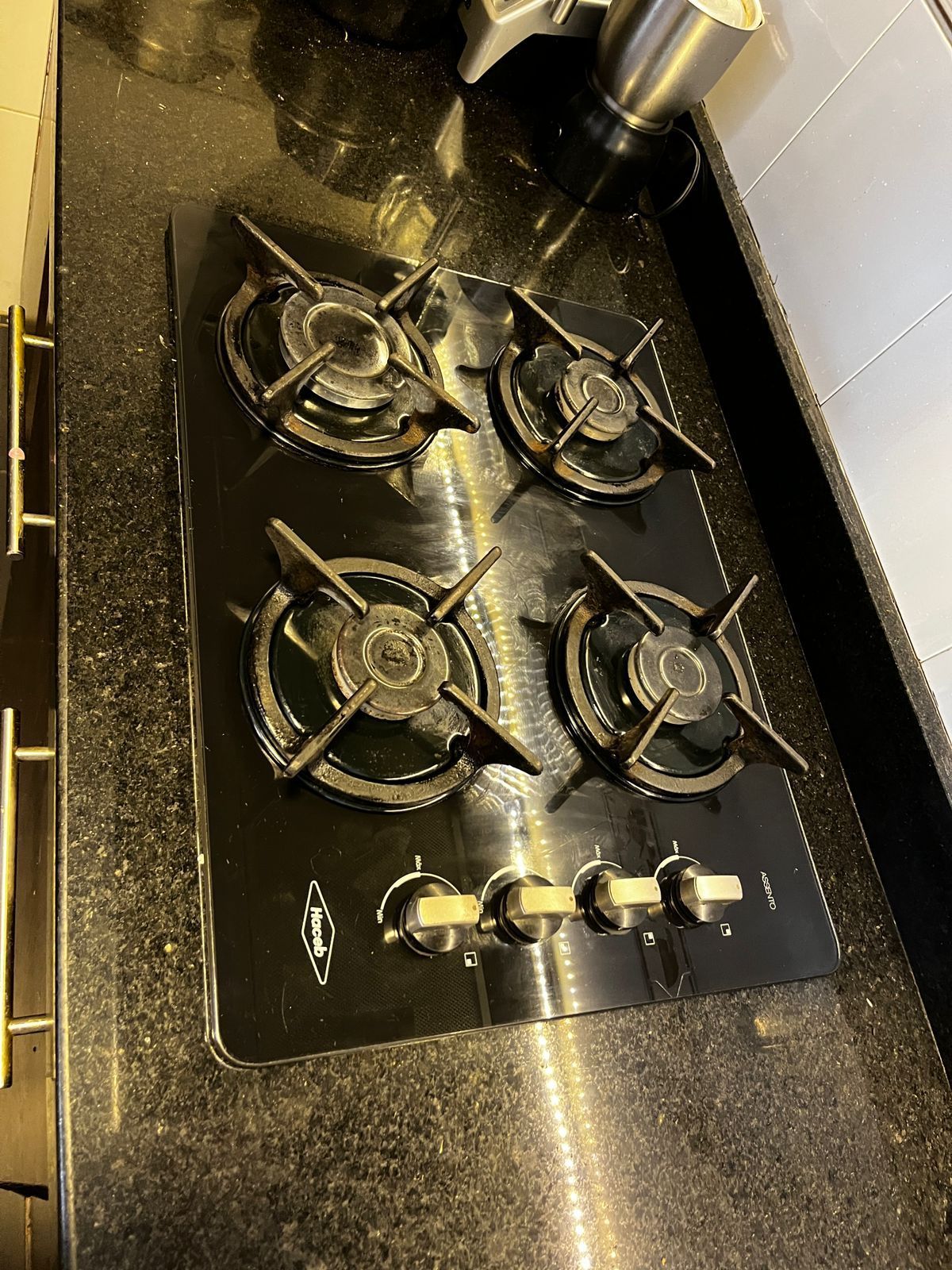 Una cocina a gas de cuatro quemadores con perillas de control colocadas sobre una encimera de granito negro moteado.
