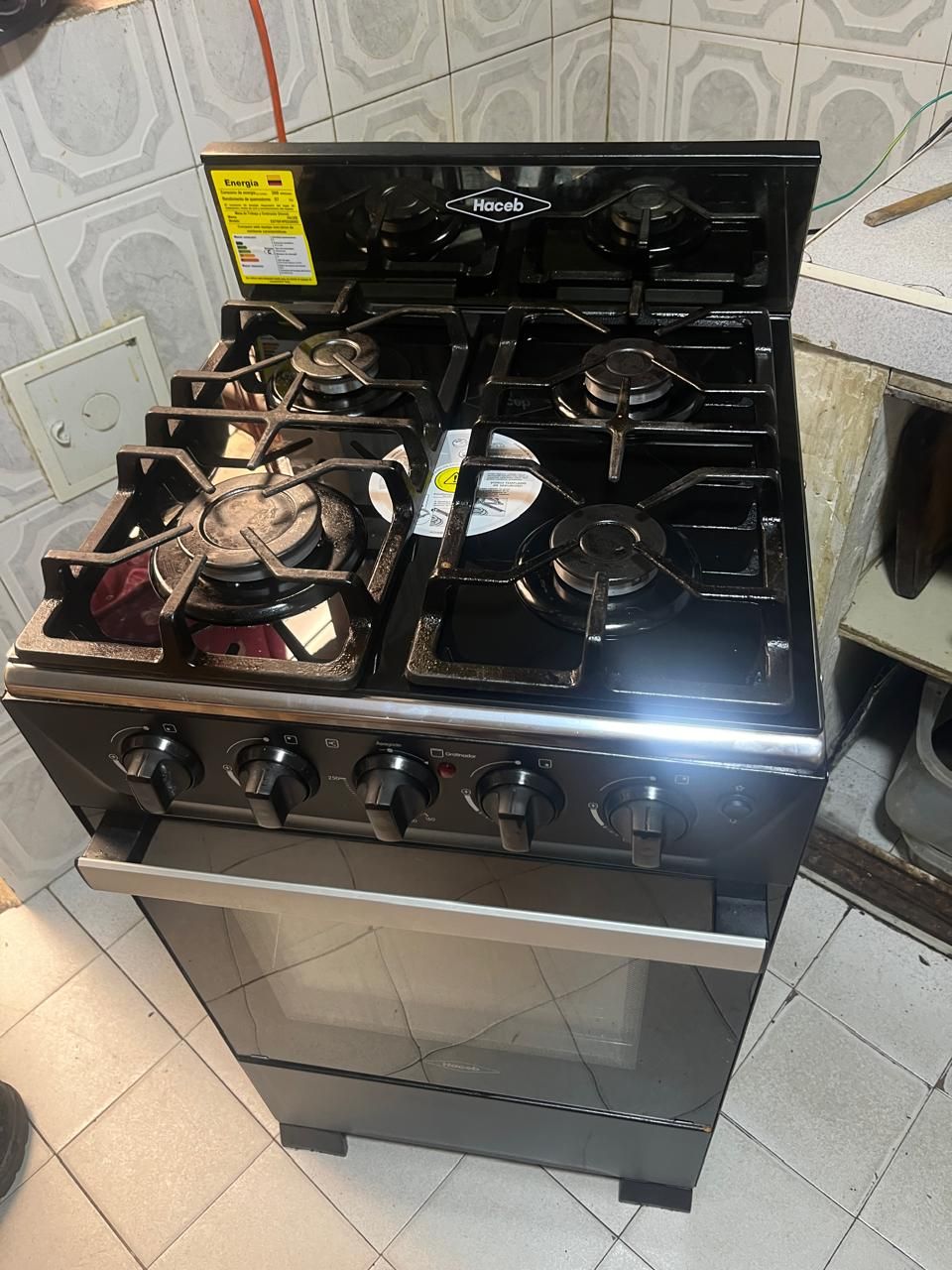 Una moderna estufa de gas de cuatro quemadores, con puerta de horno de vidrio.