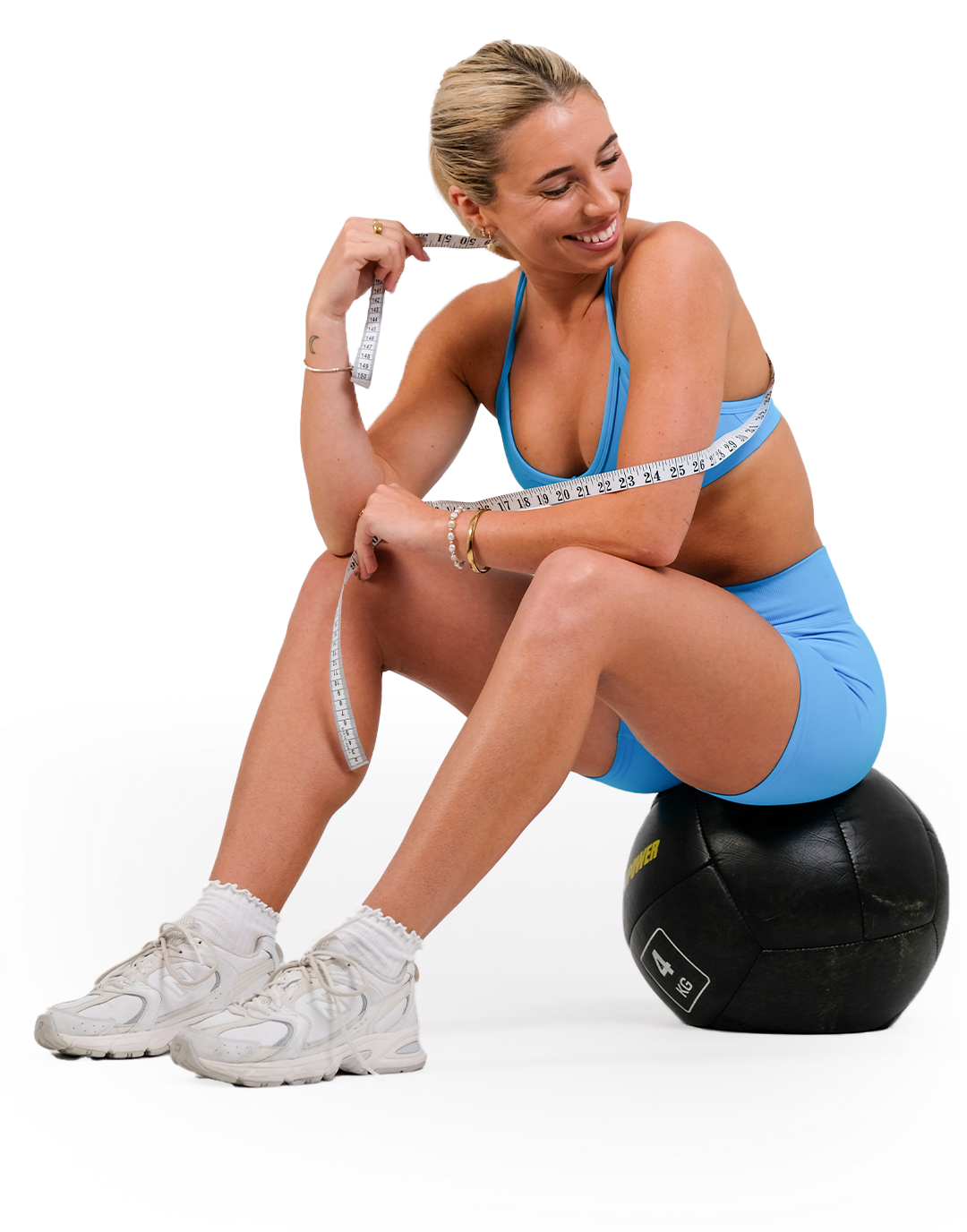 A woman is measuring her waist while sitting on a ball