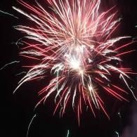 Red and white fireworks bursting against a dark night sky.