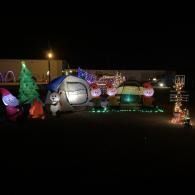 Colorful illuminated holiday yard display with inflatable decorations and glowing lights at night