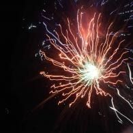 Bright red and white fireworks burst against a dark night sky
