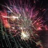 Colorful fireworks bursting against a dark sky with pink, purple, and white streaks