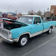 Turquoise vintage pickup truck parked in a lot with its hood open.