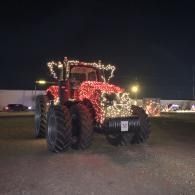 Tractor outlined with red and white lights at night on a gravel lot