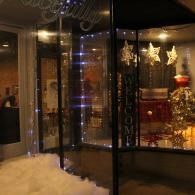 Festive storefront window with gold decorations, stars, and a glowing holiday display at night