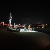 Nighttime outdoor holiday lights display with illuminated reindeer and a lit archway on a lawn