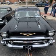 Black vintage Chevrolet car at a car show, front view, with people and other classic cars in the background