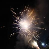Bright fireworks exploding in the night sky with white and golden sparks