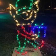 Lighted elf with a present holiday decoration glowing in red, green, gold, and blue at night