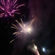 Nighttime fireworks with pink and white bursts in the sky