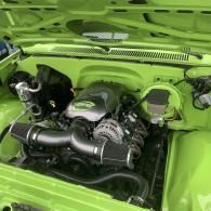 Bright lime-green car engine bay with a polished turbo setup and silver components