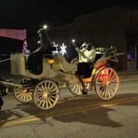 Horse-drawn carriage with glowing lights on a dark street at night