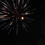 Firework bursting in the night sky with bright white streaks and a glowing center