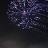 Purple firework light trails swirling in a dark sky