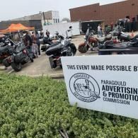 Motorcycles lined up at an outdoor event beside a white sign for Paragould Advertising & Promotion Commission