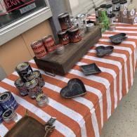 Table display of assorted mugs and candles on a red-and-white striped cloth outdoors