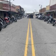 Empty street with parked motorcycles lining both sides and double yellow lines down the center