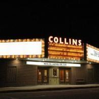 Nighttime view of the Collins theater marquee glowing above a dark entrance