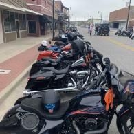 Row of parked motorcycles along a downtown street beside storefronts