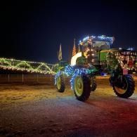 Illuminated tractor decorated with colorful lights at night, parked in an open field