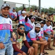 Group of people in matching jerseys sitting on bleachers at an outdoor sports field