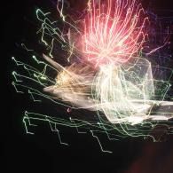 Abstract firework light trails in red, green, and white on a dark background