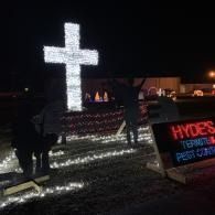 Nighttime with a large illuminated white cross and glowing Hyde's sign in the front