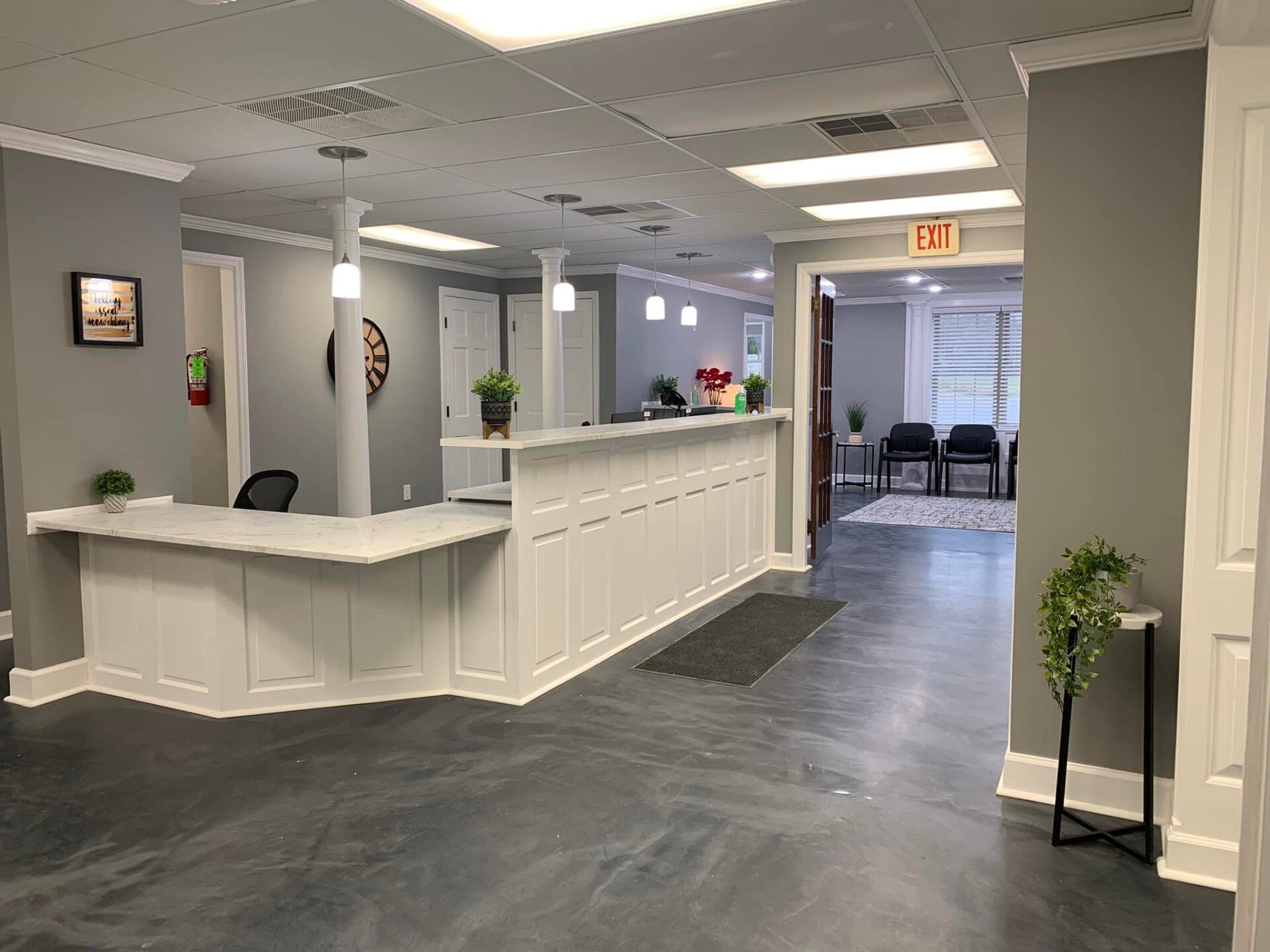 Reception area with white desk, gray walls, and waiting area visible.