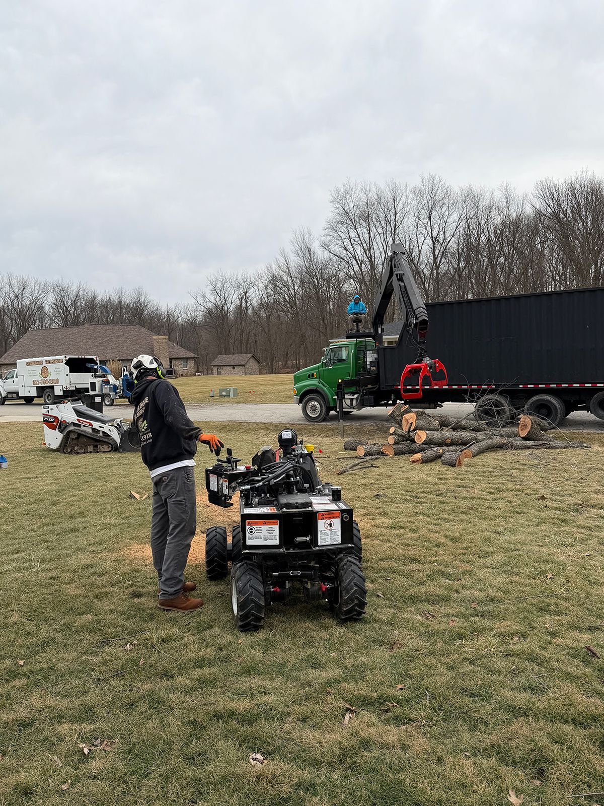Person standing by an ATV in a muddy field with trucks and equipment in the background