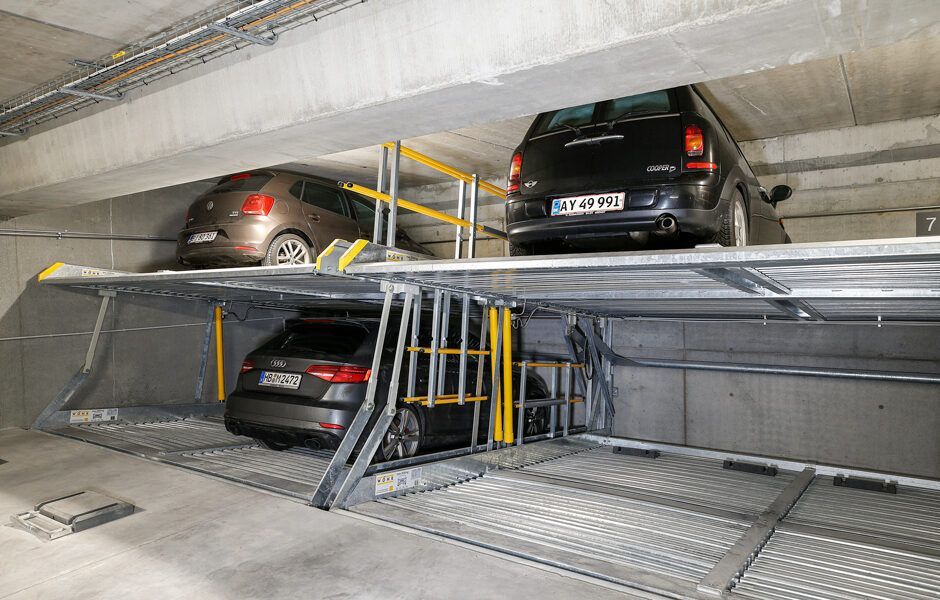 To biler er parkeret oven på hinanden i en parkeringskælder.